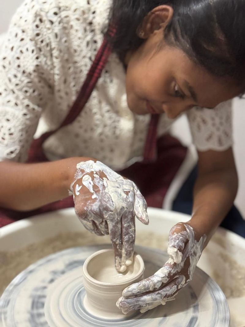 Student shaping a bowl at Mudcast